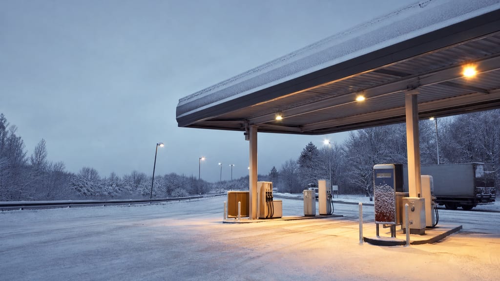 Illustration Station d’aire d’autoroute sous la neige en France, auvent éclairé — ambiance station-service type TotalEnergies — Rue Charles Beauhaire à Saint-Jean-de-la-Ruelle, près d’une autoroute (photo éditoriale, non contractuelle)