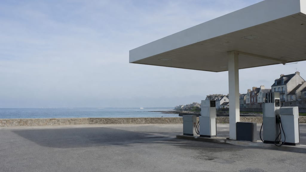 Illustration Petite station-service près du littoral français, ciel marin et auvent simple — ambiance station-service type TotalEnergies — Centre Commercial Alma, 10 Rue B à Rennes, en ville (photo éditoriale, non contractuelle)